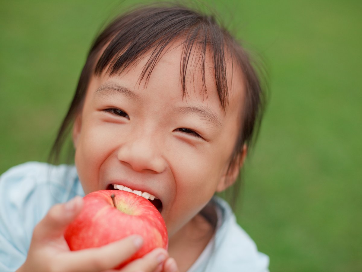 A child eating a fresh apple outdoors